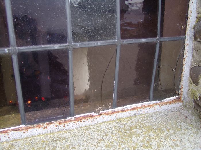 Detail van de schades en het roestige kozijn