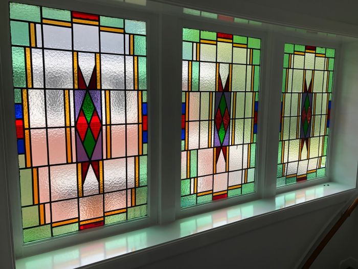 Glas in lood achter voorzetramen, doorgezakt en met reparaties